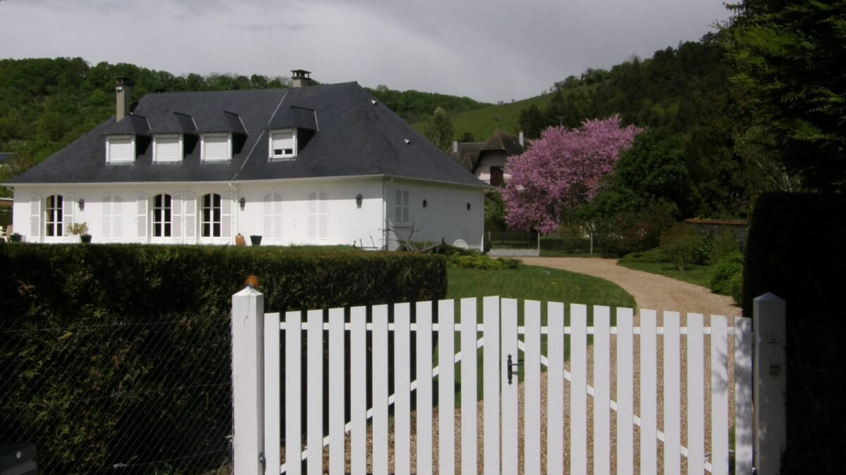 White wooden fence gate in front of a house, from our 6-foot privacy fence cost guide