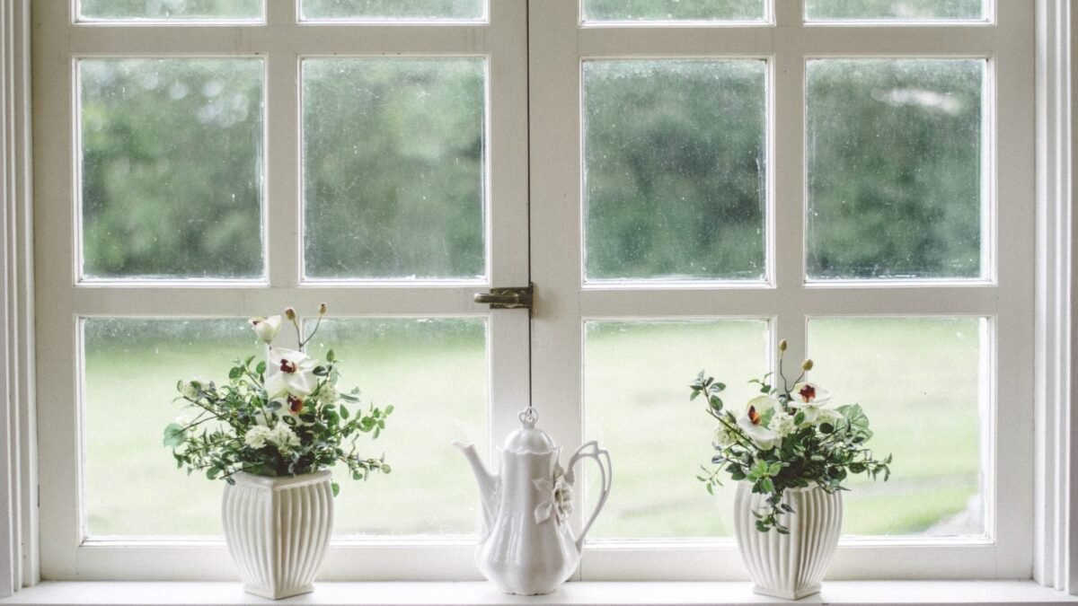 White multi-pane windows with flowers on the sill, from our basement windows guide