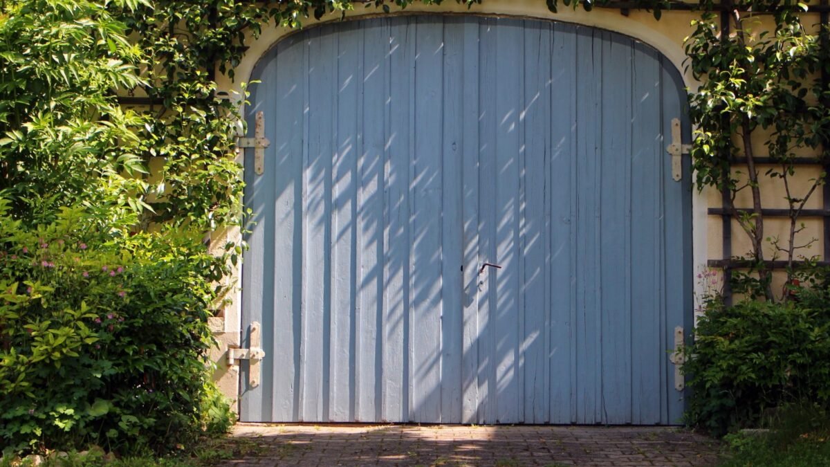 Blue wooden garage door with weathered panels, a candidate for garage door panel replacement