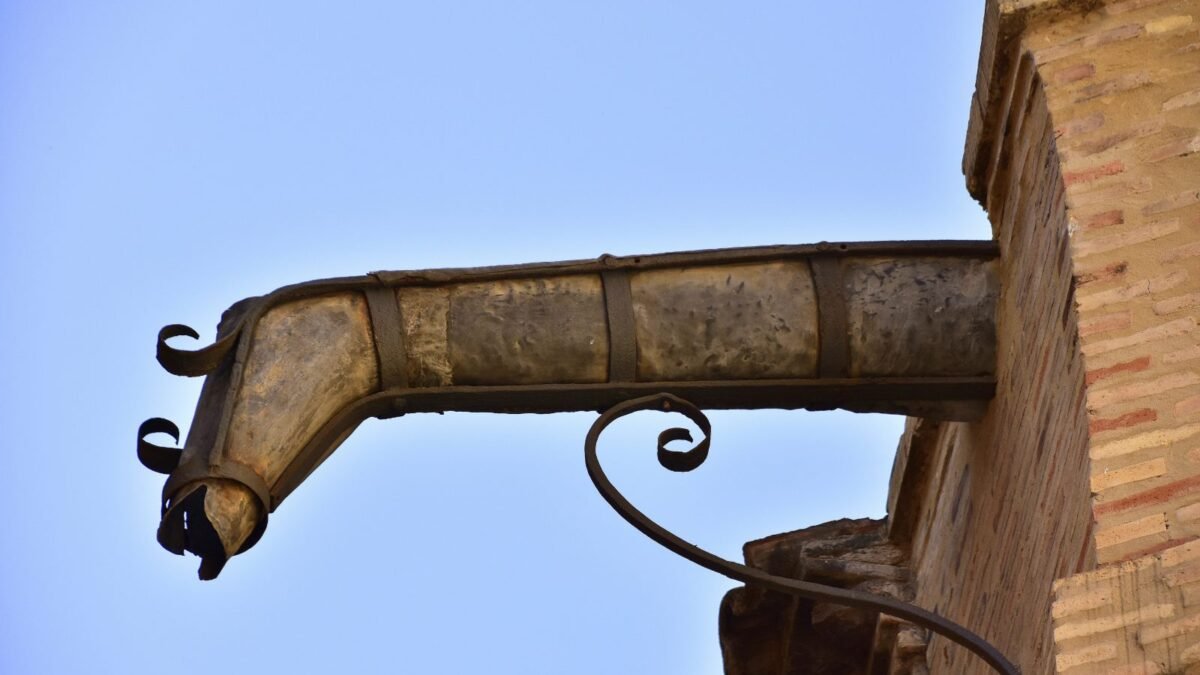 Old metal gutter spout on a brick wall, illustrating gutter cost per foot by material