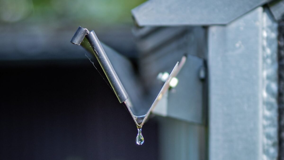 Close-up of a metal gutter with a drop of rainwater, from our guide to how much gutters cost