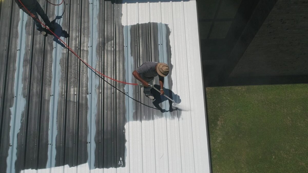 Roofer spraying coating on a metal roof, from our guide to new roof permits