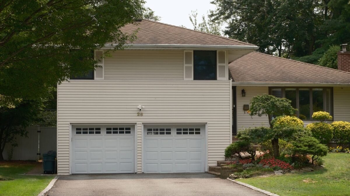 Suburban house with two white raised-panel garage doors and a driveway