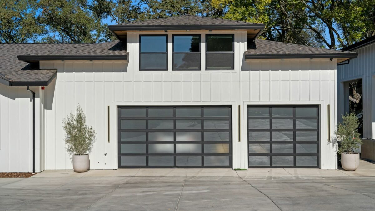 White modern house with two black-framed full-view glass garage doors