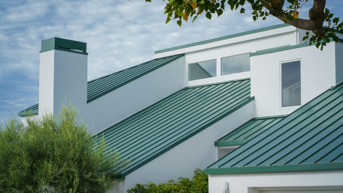 White house with a green standing seam metal roof and raised vertical seams